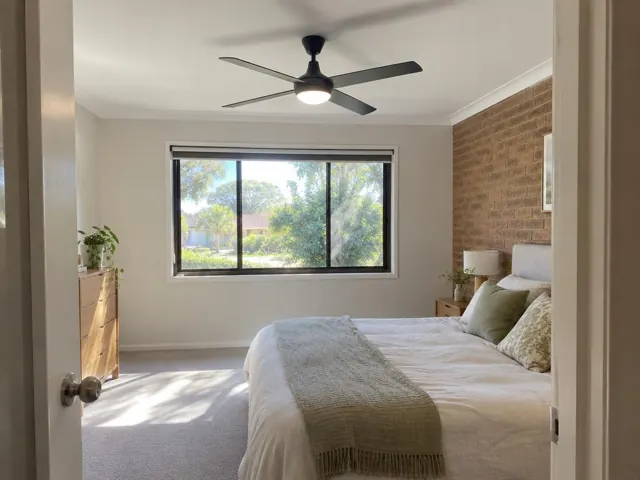 Bedroom with a black ceiling fan on a white ceiling above a bed and window in St Ives